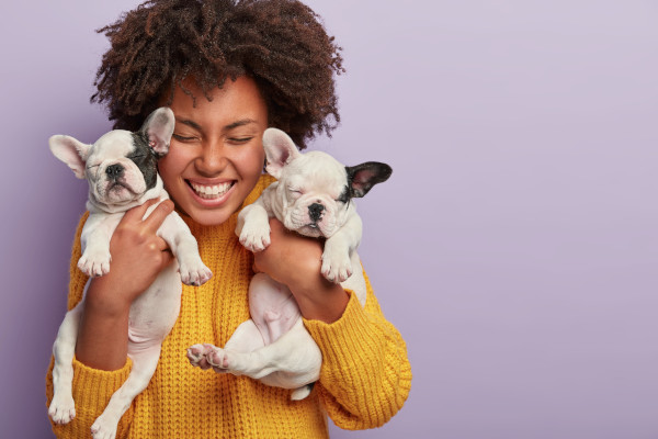 African american woman wearing yellow sweater holding puppies - Image by wayhomestudio on Freepik